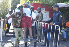 An elderly woman is assisted to a polling station