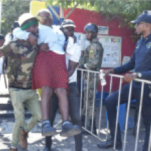 An elderly woman is assisted to a polling station